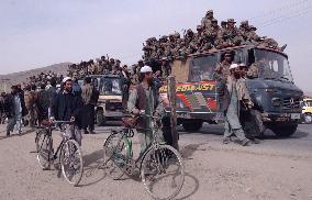 Kabul residents walk by Northern Alliance trucks